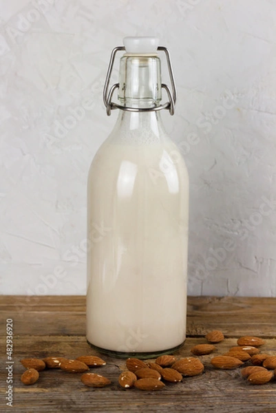 Fototapeta A bottle with alternative dairy free almond milk on wooden table. Lactose free beverage