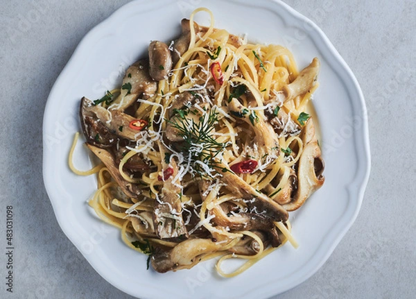 Obraz Oyster Mushroom linguini pasta closeup on white plate. Mushroom traditional pasta with parmesan cheese and red chilly peppers garnished with dill and parsley. Oyster mushroom linguini pasta