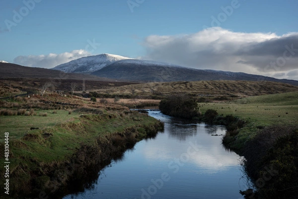 Fototapeta A river at the edge of Wild Nephin National Park in Ireland. Snow on the mountaintops of Wild Nephin Mountains. 