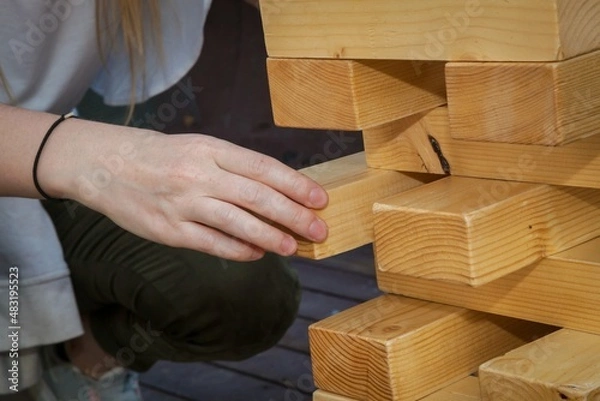 Obraz A falling tower game, hands holding wooden bars in close-up.