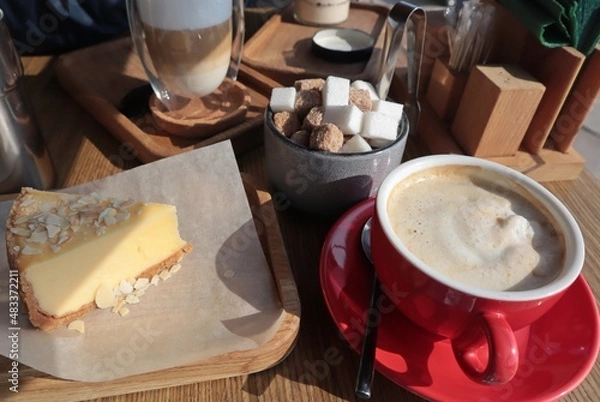 Fototapeta There is a mug of coffee, a cake and sugar on the table in the cafe.