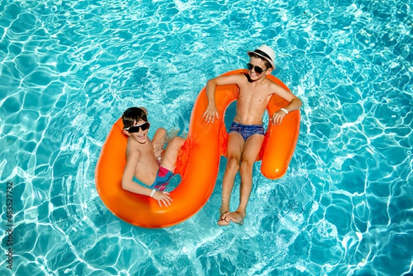 Fototapeta child in the pool. the boys in the pool are swimming on the orange circle.