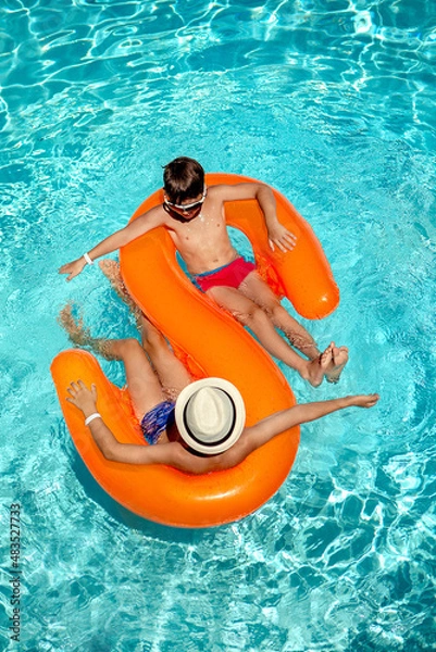 Fototapeta child in the pool. the boys in the pool are swimming on the orange circle.