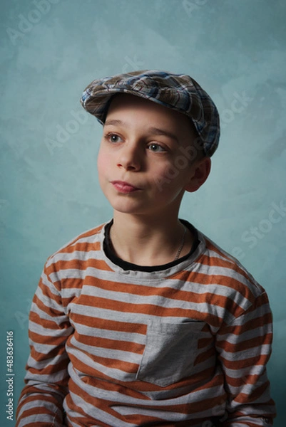 Obraz portret młodego chłopaka w czapce na niebieski tle
