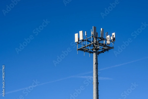 Fototapeta Closeup of wireless cell site antennas on a monopole tower against a clear blue sky
