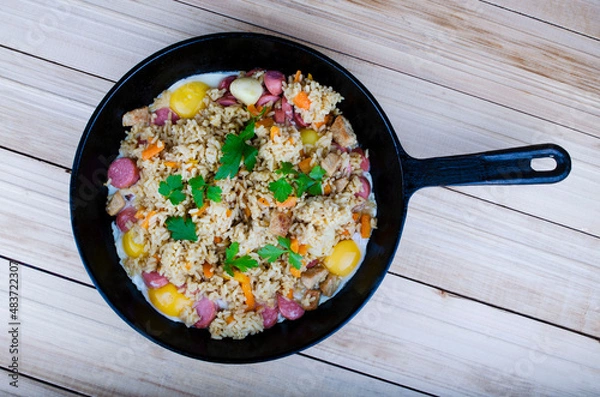 Obraz Cast iron frying pan with a pilaf dish of meat and rice with spices