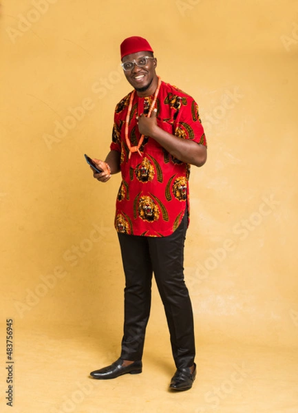 Fototapeta Igbo Traditionally Dressed Business Man Standing with Phone in Hand and smiling
