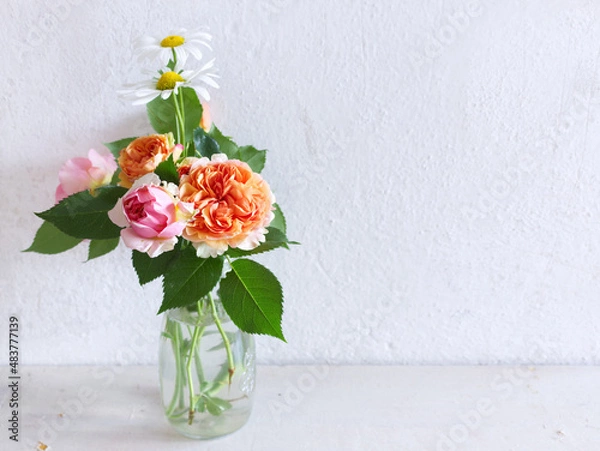 Obraz Spring flowers in a glass vase on a wooden table. Blurred kitchen background. Bouquet of roses and Leucanthemum. Contemporary elegant scandi interior.