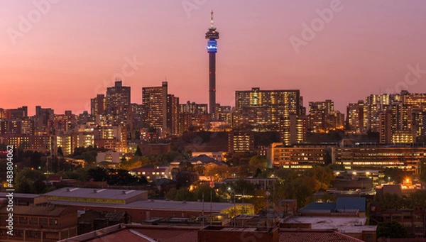 Fototapeta A horizontal panoramic cityscape taken after sunset, with a pink glow in the sky, of the central business district of the city of Johannesburg, South Africa