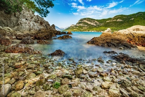 Obraz Wybrzeże i morze Chorwacji z kamienną plażą i niebieskim niebem z białymi chmurami