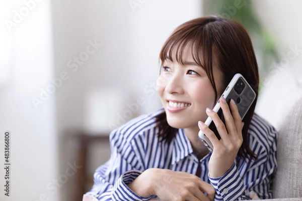 Fototapeta ソファに寝転んで電話する女性