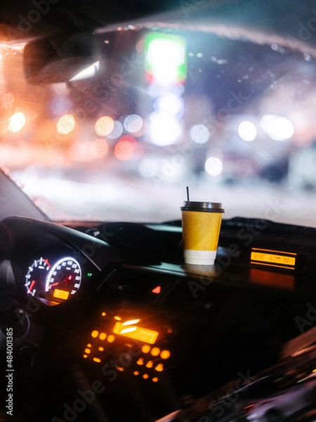 Obraz A glass of coffee is in the car against the backdrop of night city lights