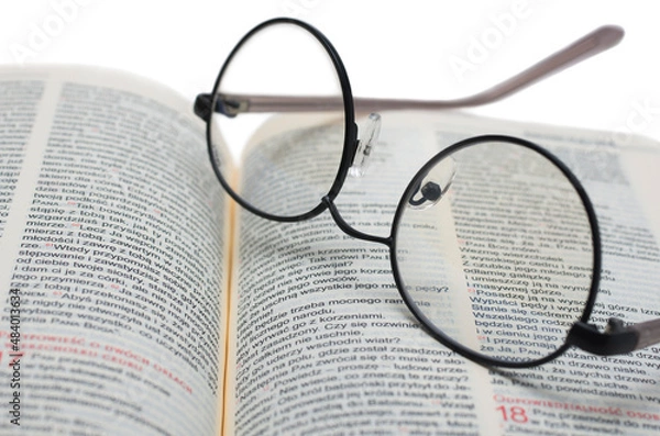 Obraz Glasses lying on the Bible in Polish isolated on a white background
