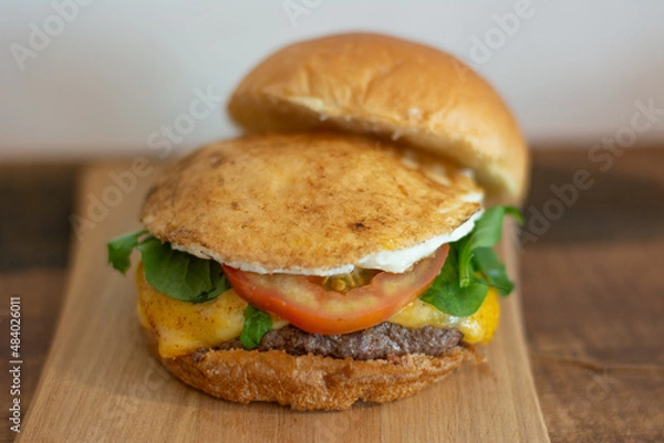 Obraz Cheeseburger with open bread, showing fried egg, tomato, arugula, cheese and patty.