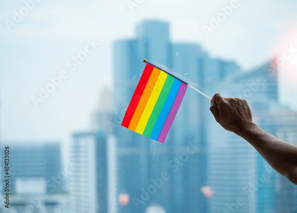 Fototapeta Office building background with a rainbow gay pride flag on the senior man's hand in the business office