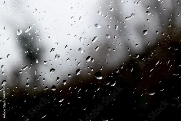 Fototapeta Raining dropping on the glass door window, bubble transparent outside black and white background. Focus foreground 
