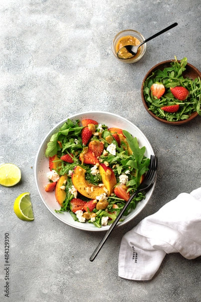 Fototapeta salad bowl with arugula, strawberry, cottage cheese, nectarine and peanut paste. healthy eating concept