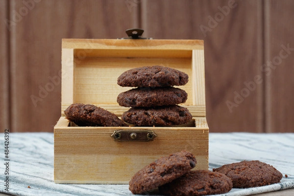 Obraz Dark chocolate cookies inside the treasury box over wooden background