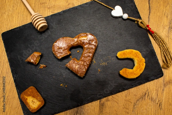 Obraz A piece of cookies, spoon for honey, heart shape cookie and white hearts on black stone plate. Love valentine concept. Flat lay