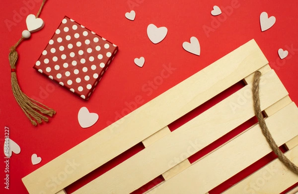 Obraz Wooden palette, gift box with polka dots and white hearts on a red background. Love valentine concept. Flat lay