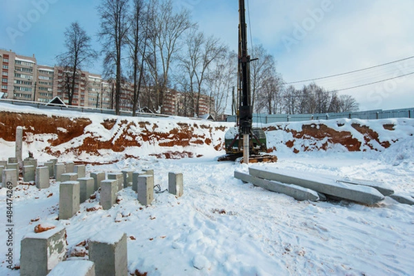 Fototapeta clogged piles in the foreground of a new house under construction in winter