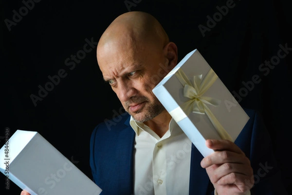 Obraz A man in a business suit opened a congratulatory box and was very surprised by the gift. Congratulations and gifts for men.