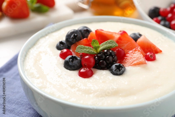 Fototapeta Delicious semolina pudding with berries in bowl on table, closeup