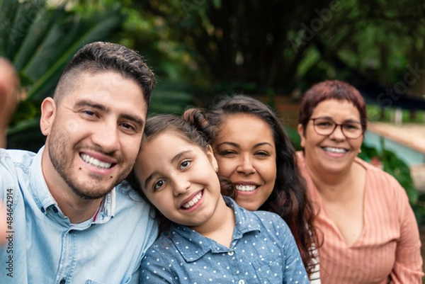 Fototapeta brazilian family generations looking at camera and smiling for selfie outside in the garden