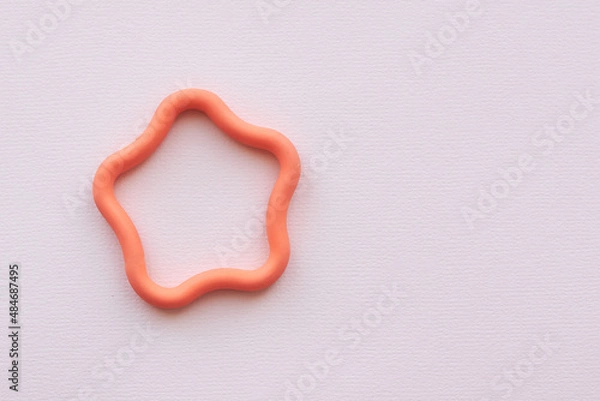 Fototapeta Decorative orange rubber star lies on a white background. Copy space.