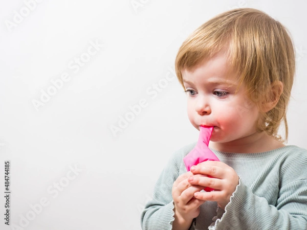 Obraz little girl trying to inflate a balloon with her lips