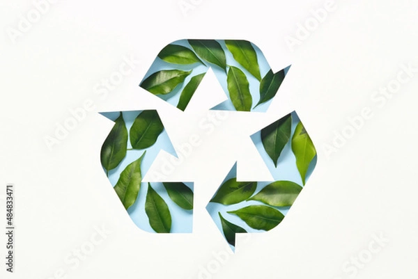 Fototapeta Recycle symbol made of cut paper and green leaves on blue background. Reuse, reduce, recycle concept