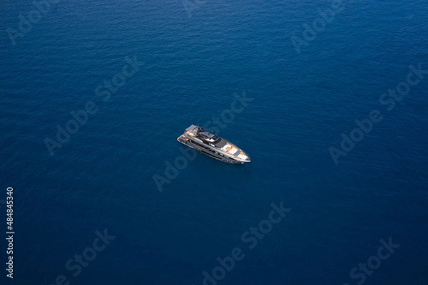 Fototapeta Big gray super boat on the water aerial view. Big yacht for millionaires in the sea drone view. Luxurious gray blue Mega yacht on dark water top view.