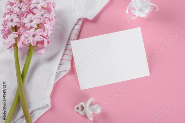 Fototapeta Baby shower invitation 5x3,5 card mockup with baby accessories girl bodysuit, nipple or baby's dummy, gift box and confetti and pink hyacinth flowers with copy space on pink pastel color background