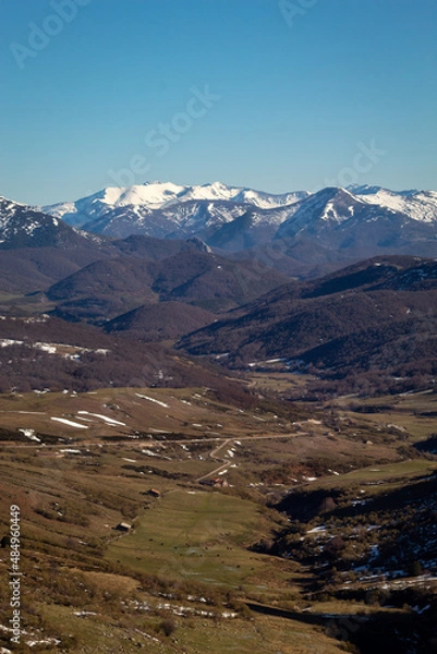 Fototapeta The last snows melt in the valley while in the distant peaks everything remains white.