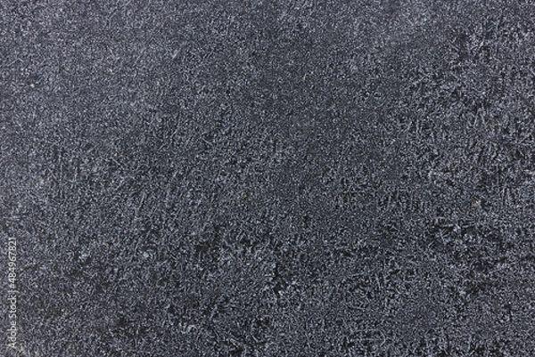 Fototapeta Frozen pattern of hoarfrost and frostwork structure on the dark windshield glass. Color photo for background. 