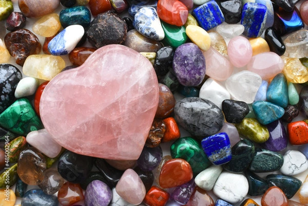 Fototapeta A top view image of a large variety of healing crystals with a large rose quartz crystal heart. 