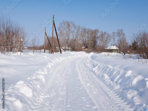 Fototapeta Winter rural road and trees in snow and sun at sunset.