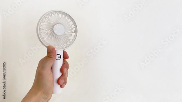 Fototapeta 左手で持った携帯扇風機