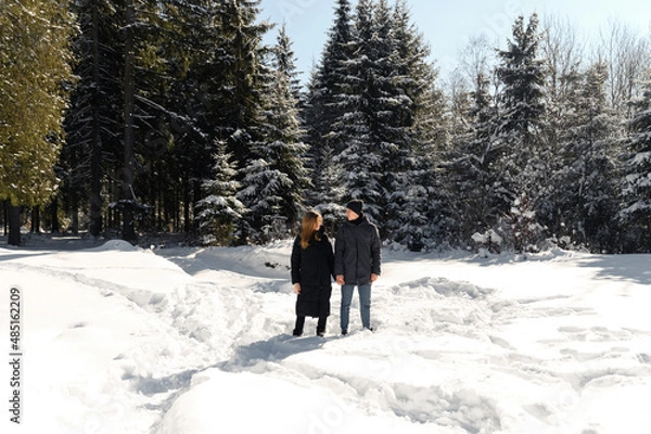 Fototapeta young couple fooling around while on a winter walk near the forest. a general plan of a couple in love against the backdrop of winter nature.