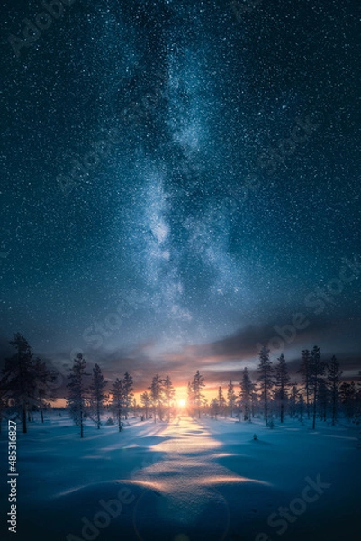 Fototapeta Beautiful sunrise over snowy forest with an epic milky way on the sky