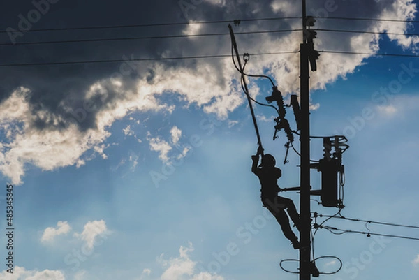 Fototapeta The silhouette of power lineman replacing a transformer and hotline clamp, bail  clamp. Using clamp stick grip all type, wearing personal protective equipmen,