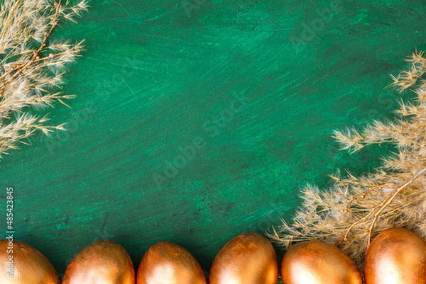 Fototapeta Golden Easter eggs and golden branches, reeds on a green watercolor background. Banner. Layflat. Space for text 