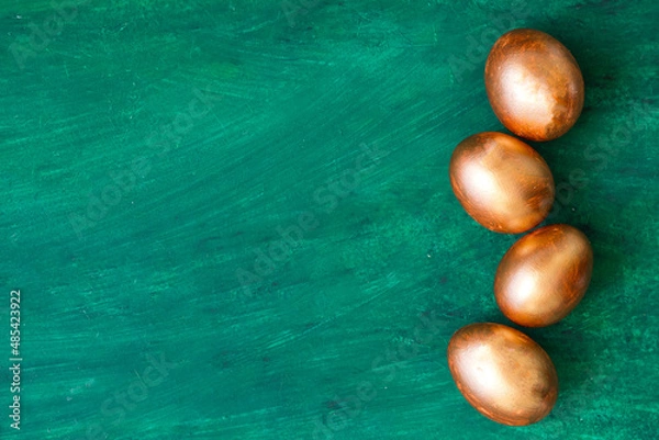 Fototapeta Golden Easter eggs and golden branches, reeds on a green watercolor background. Banner. Layflat. Space for text 
