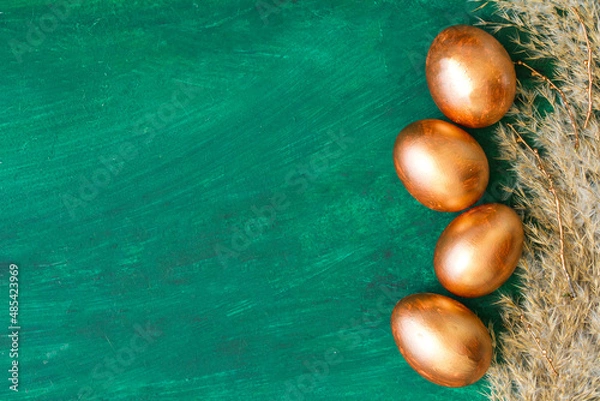 Fototapeta Golden Easter eggs and golden branches, reeds on a green watercolor background. Banner. Layflat. Space for text 