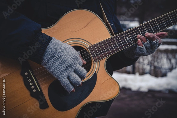 Fototapeta Weathered hands playing beat up guitar 