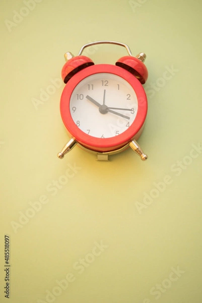 Fototapeta new red round clock on pale green table, copy space.