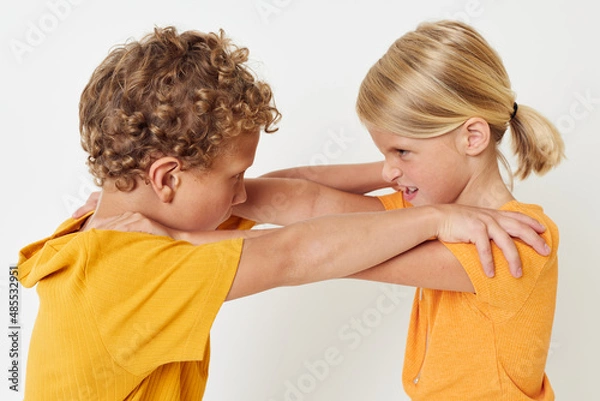 Fototapeta picture of positive boy and girl in yellow t-shirts standing side by side childhood emotions unaltered