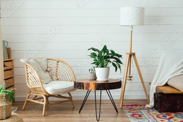 Obraz Rattan armchair and floor lamp in living room interior with plants. Cozy interior in boho style. Real photo