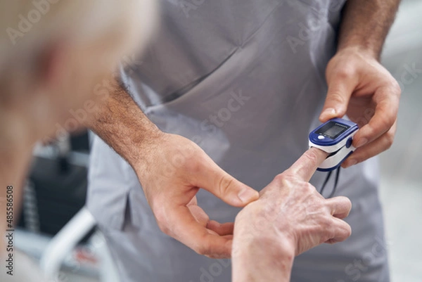 Obraz Doctor applying pulse oximeter to patient finger
