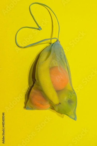 Fototapeta  Fruit lies in a reusable bag for shopping on a yellow background. Vertical photo. High quality photo